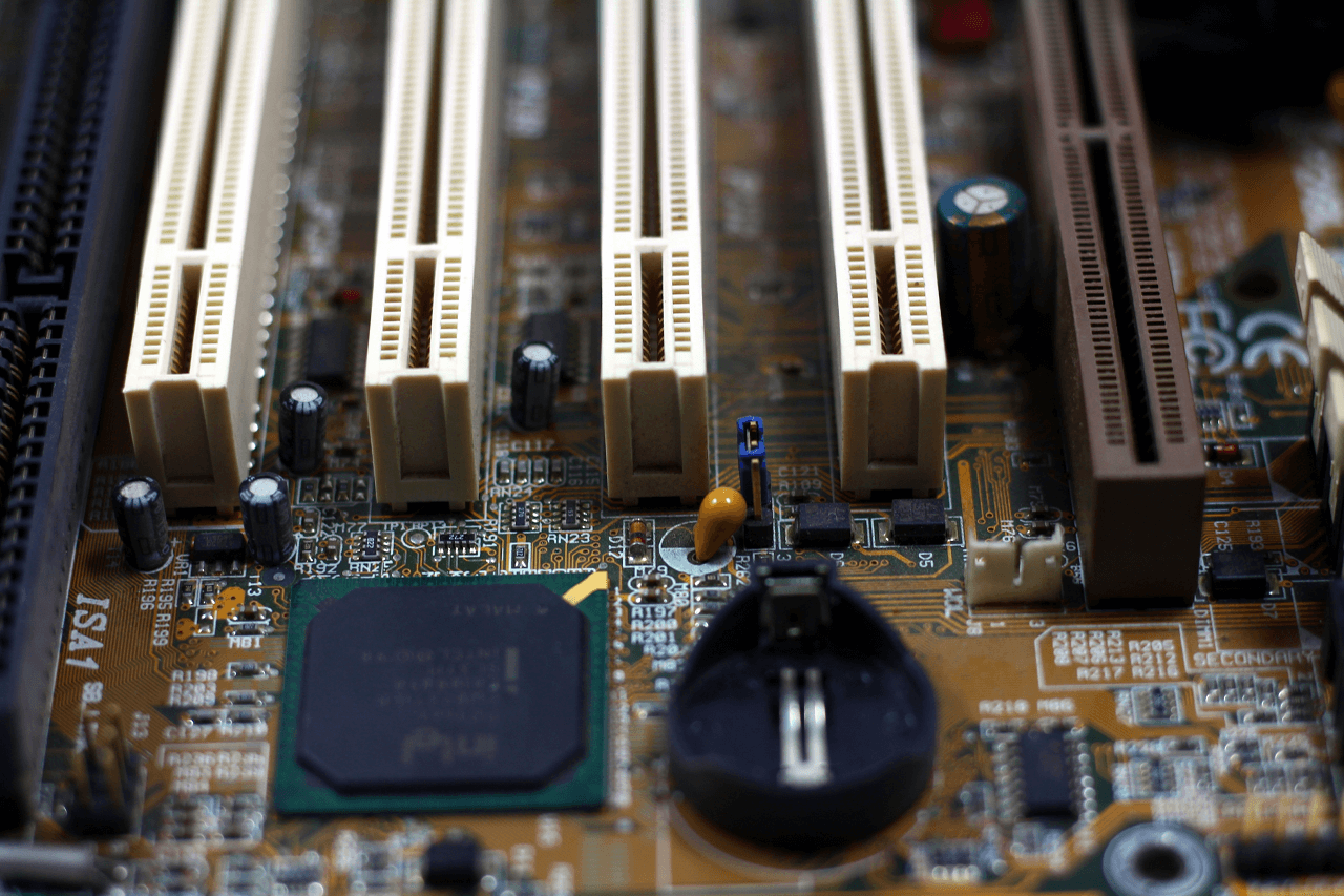 A computer motherboard displaying four empty RAM slots.